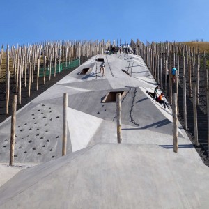 Playscape be-Mine is about translation of industrial landscape to a playful recreational environment. Especially interesting is the concrete linear play element that much like the old mining shafts runs through an array of wooden slabs that were supporting the underworld. Furthermore, climbing on the concrete gets increasingly more difficult towards the top and requires some team work, which, according to the designers, acts "as an immaterial reference to the hard physical work of the old mine-workers, who had to trust one another unconditionally". Reaching the top immediately pays off the effort of climbing. A poetic and beautifully designed coal circle offers an epic view on the surrounding landscape, industrial remains and of course the coal. The storytelling is intelligently manifested through means of abstraction.